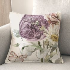 a pillow with flowers on it sitting on a couch in front of a window and a butterfly