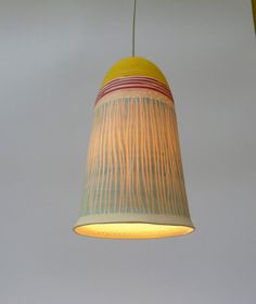 a yellow and red lamp hanging from a ceiling fixture with a white light behind it