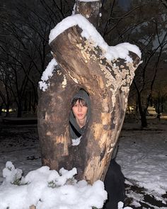 a person sitting in front of a tree stump with snow on it