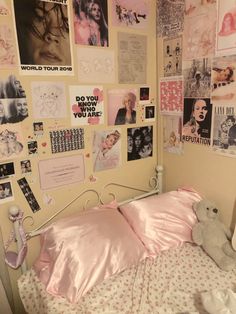 a bed with pink sheets and pictures on the wall next to a teddy bear sitting on top of it