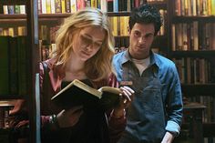 a man and woman looking at a book in a library