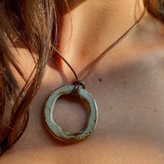 a close up of a woman wearing a necklace with an oval pendant on it's neck