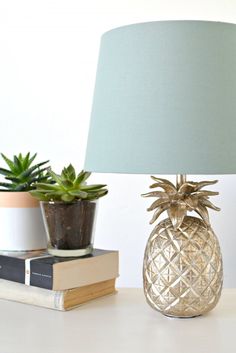 a pineapple lamp sitting on top of a table next to books and a potted plant