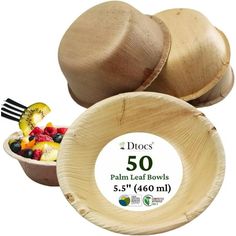 a wooden bowl filled with fruit next to two spoons and a plastic container that says 50 palm leaf bowls