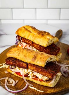 two sandwiches are on a cutting board with onions and meats in the middle, along with text that reads cajun blackened tofu sandwich with creamy sriach coleslaw