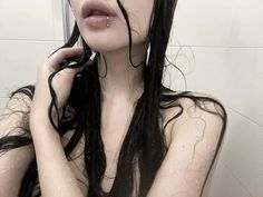 a woman with wet hair is standing in the shower and holding her hand to her face