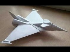 a white origami fighter jet sitting on top of a wooden table