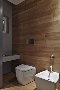 a white toilet sitting next to a sink in a bathroom on top of a hard wood floor