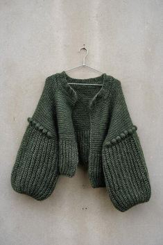 a green sweater hanging on a white wall