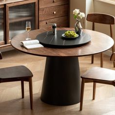 a wooden table with two chairs and a bowl of fruit on it