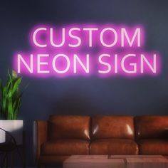 a neon sign that reads custom neon sign in front of a couch and coffee table