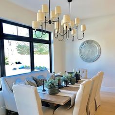 a dining room table with white chairs and a chandelier hanging from the ceiling