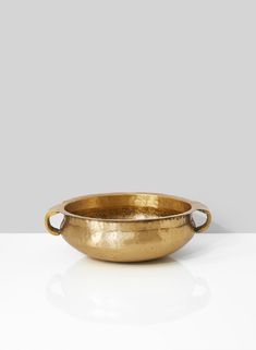 a gold bowl sitting on top of a white table