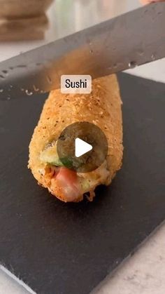 a sushi roll being cut into pieces with a large knife on top of it