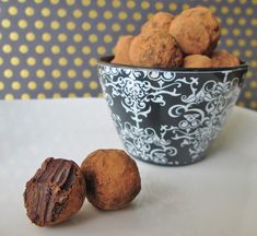 a bowl filled with chocolate truffles next to a cup full of nuts on a table