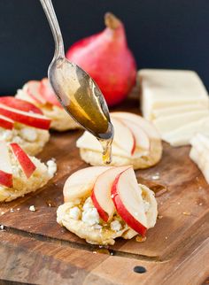 an apple and cheese appetizer is being drizzled with syrup from a spoon