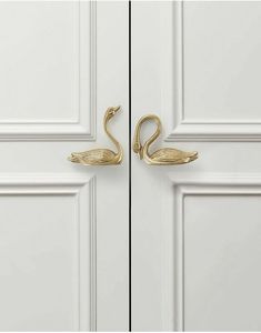 two brass swan hooks on the side of a white door