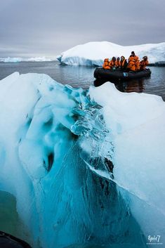 an iceberg floating in the water with people on it's boat near by