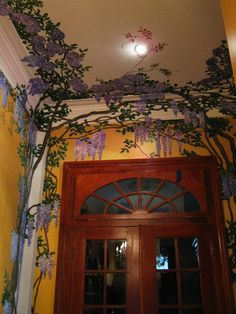 a doorway with purple flowers painted on the ceiling and above it is a wooden door