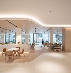 an empty room with tables and chairs in it, while someone is walking past the counter