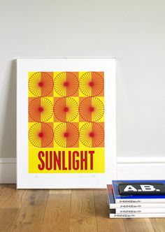 a yellow and red poster sitting on top of a wooden floor next to a stack of books