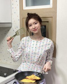 a woman holding a frying pan with food in it