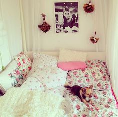 a small dog laying on top of a bed covered in white sheets and pink pillows