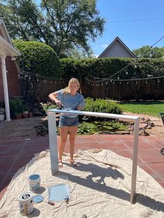 a woman standing next to a metal rail on top of a patio covered in sand