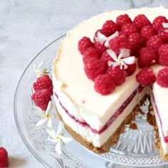 a cheesecake with raspberries is on a glass plate