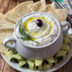 a bowl of hummus and cucumber on a plate next to crackers