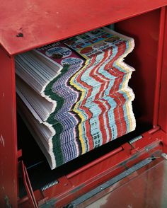 stacks of papers are stacked in a red cabinet