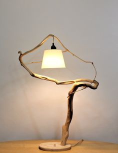 a wooden table with a lamp on top of it and a tree branch in the middle