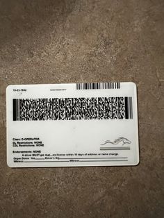 a white ticket with black and white lines on the front is sitting on a brown surface