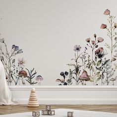 a white room with flowers painted on the wall and wooden blocks in front of it