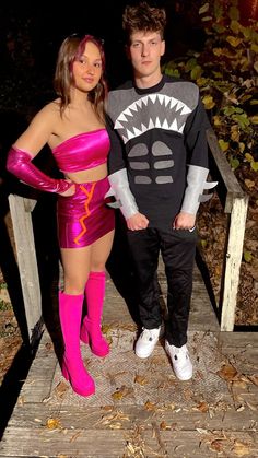 a man and woman in costume posing for a photo on a wooden bridge at night