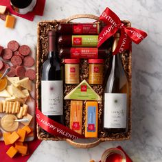an assortment of wine, cheese and crackers in a basket