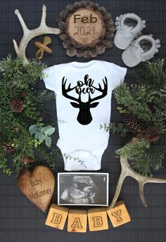 a baby's bodysuit surrounded by deer antlers, pine cones and other items