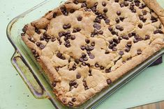 a cookie cake sitting on top of a metal pan covered in chocolate chip toppings