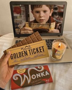 a person holding up a golden ticket next to a laptop