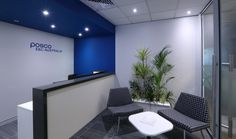 an office with blue and white walls, black chairs and a plant in the corner