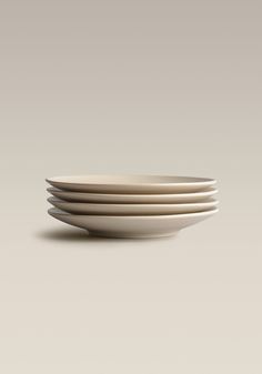 four white plates stacked on top of each other in front of a gray background,