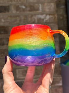 a hand holding a rainbow colored coffee cup