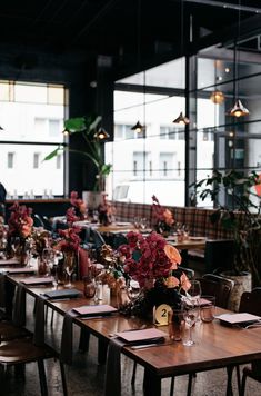 the tables are set with flowers and place settings for an event or gathering in front of large windows