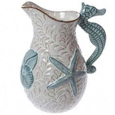 a white and blue ceramic vase with seahorses on the side, holding a starfish