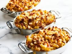 three pans filled with macaroni and cheese on top of a marble counter