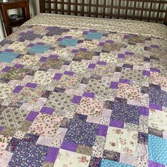 a bed with a purple and blue quilt on it