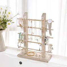 a white vase filled with flowers and jewelry on top of a table next to a window