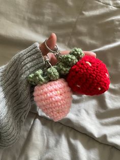 a hand holding two knitted fruit keychains