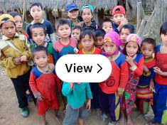 a group of young children standing next to each other in front of a straw hut