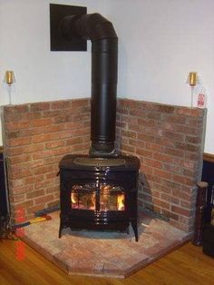 a wood burning stove sitting inside of a living room next to a brick wall and wooden floor